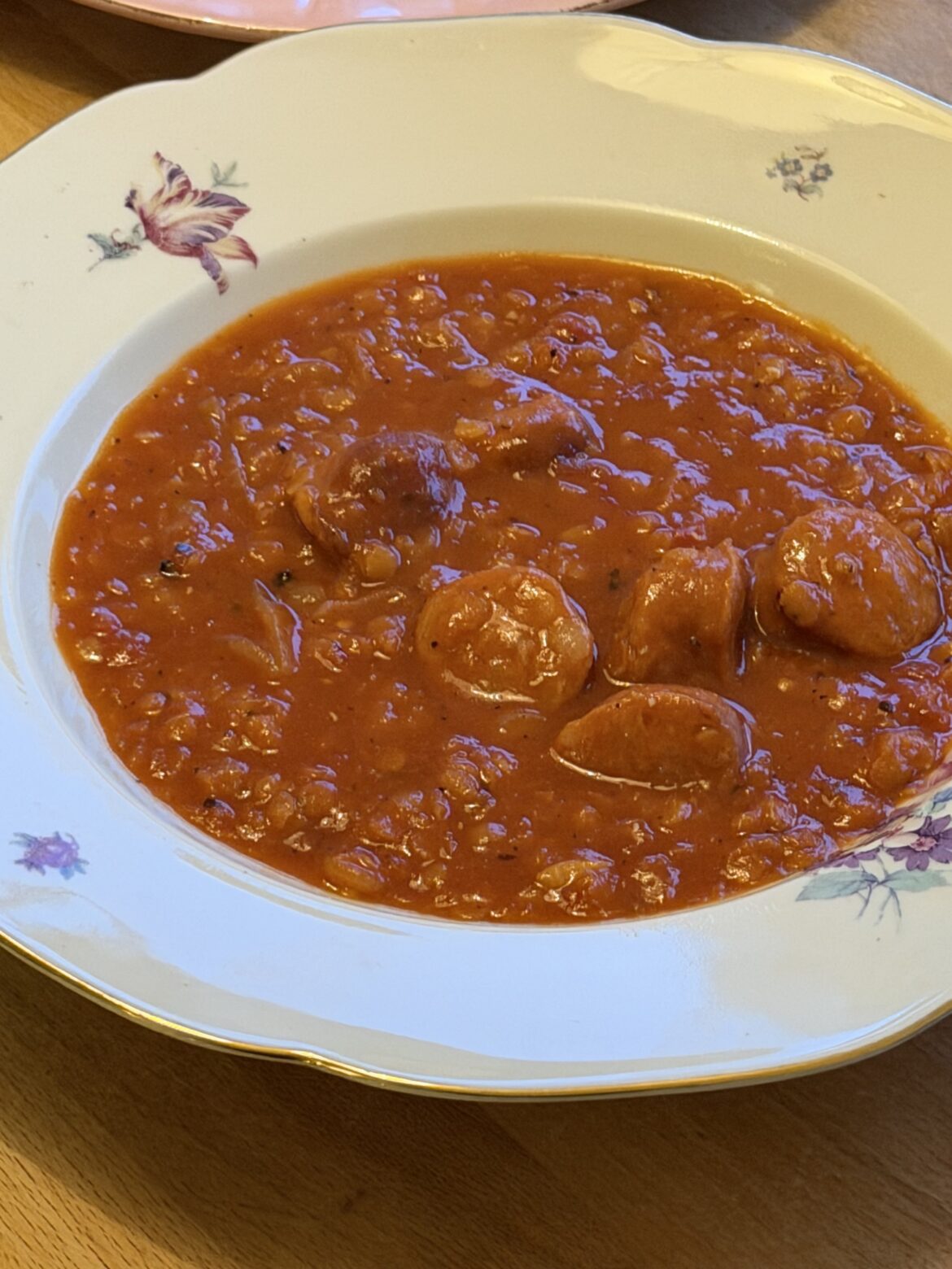 Linssoppa med chorizo i en vit tallrik med guldkant